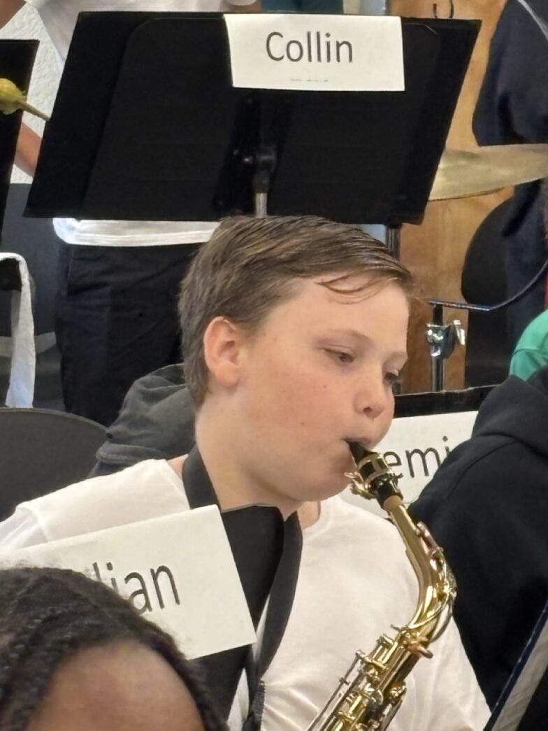 a young boy playing a saxophone in a band
