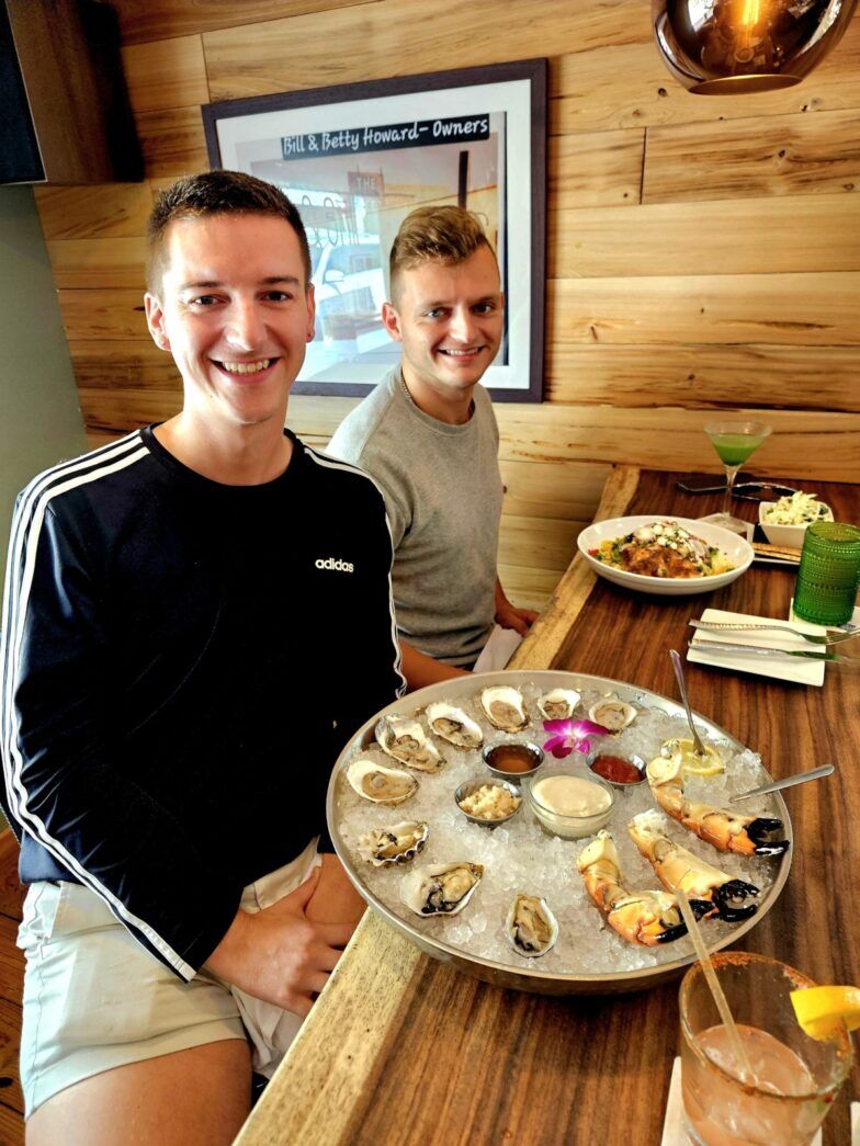 two men sitting at a table with a tray of oysters