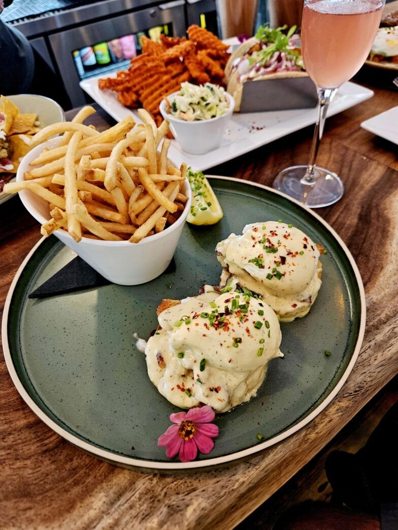 a wooden table topped with plates of food and a glass of wine