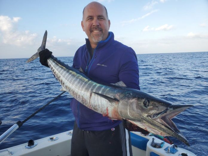 Client-with-wahoo a man holding a fish on a boat