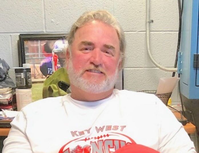 Coach John Hughes a man in a white shirt holding a red frisbee