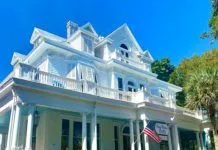 KEY WEST’S STATELY CURRY MANSION INN TO CHANGE HANDS a large white house with a flag on top of it