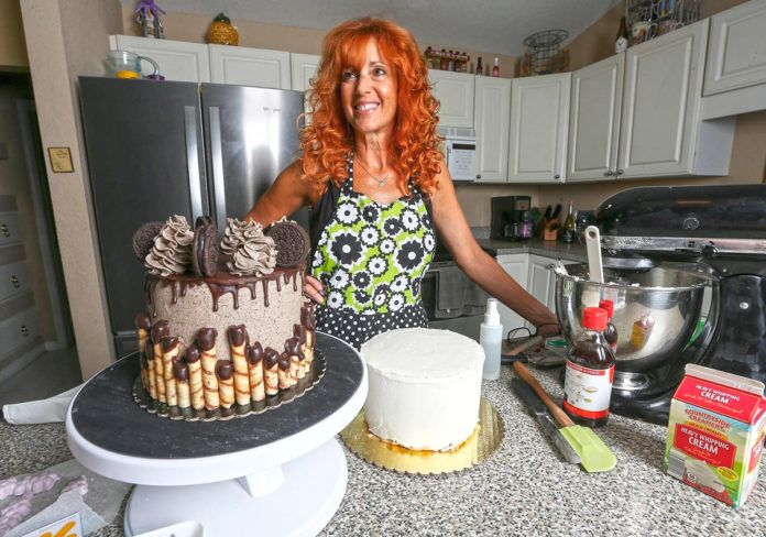 a woman standing next to a cake on top of a counter