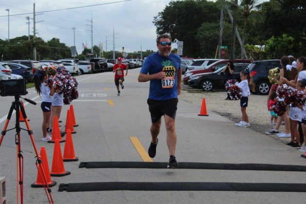 a man running in a race with other people watching