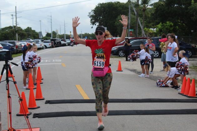 a woman running in a race with her arms in the air