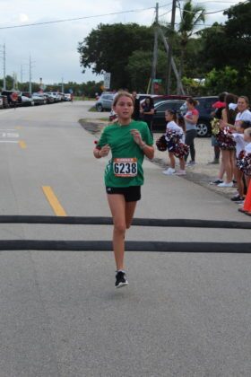 a woman in a green shirt running down a street