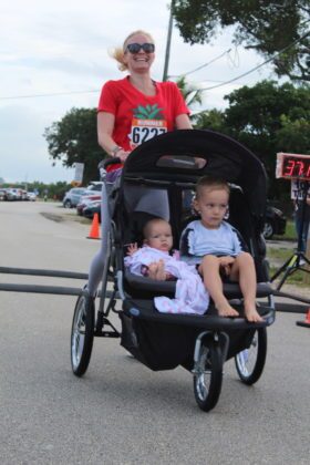 a woman pushing a stroller with two babies in it