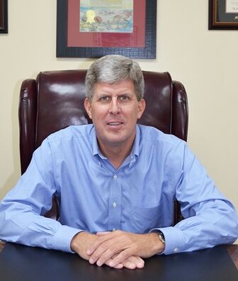 JimScholl (2) a man in a blue shirt sitting at a desk