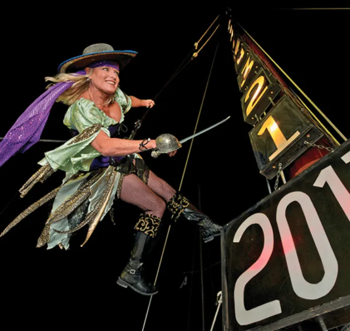 a woman dressed as a witch on top of a sign