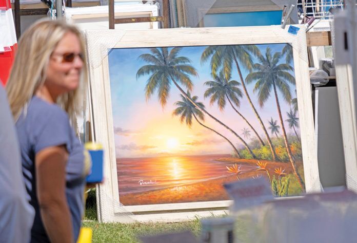 Nautical-Flea-Market-vendor a woman standing in front of a painting of a sunset