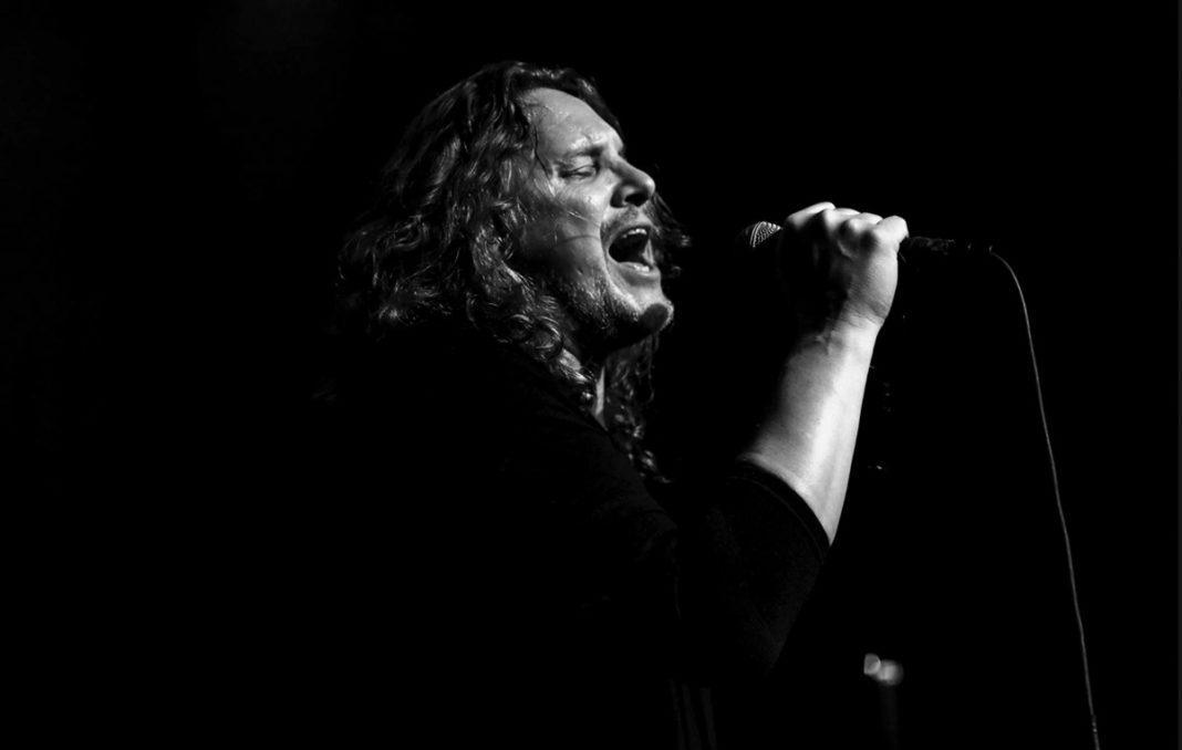 a black and white photo of a man singing into a microphone