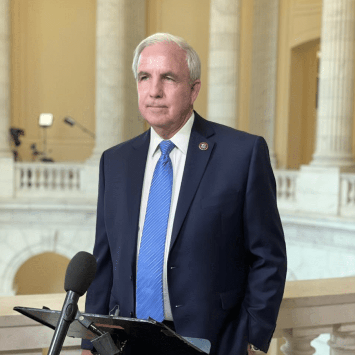 Carlos Gimenez a man in a suit and tie standing in front of a microphone