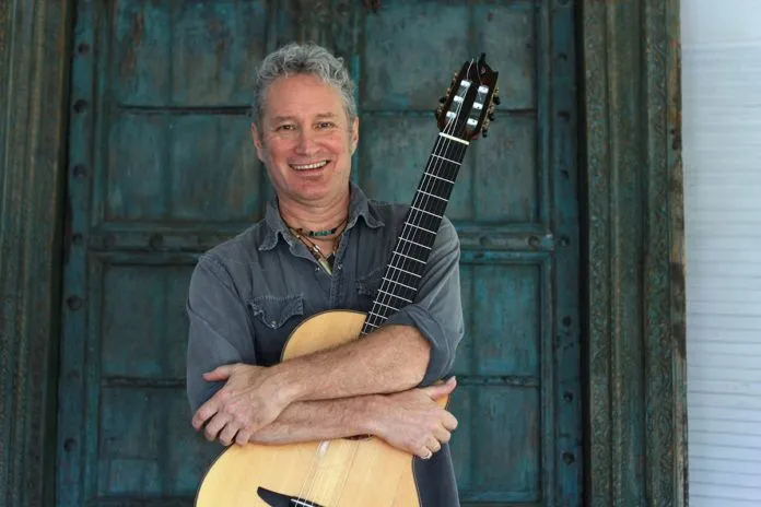 a man holding a guitar in front of a door