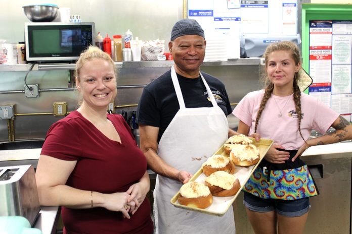 Ashley,-Bob-and-Destani a group of people standing in a kitchen