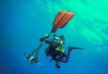 a man in a scuba suit is holding a kayak in the water