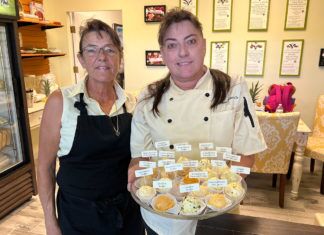 a couple of women standing next to each other holding trays of food