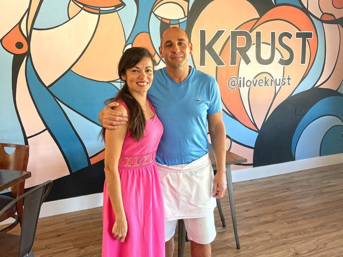 Krust-1 a man and a woman standing in front of a colorful wall