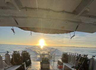 the sun is setting over the water on a boat