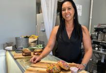a woman standing behind a counter with doughnuts on it