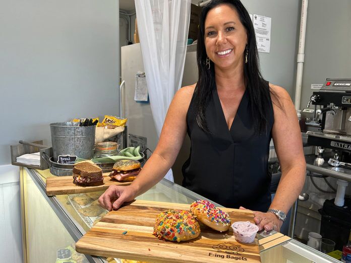 a woman standing behind a counter with doughnuts on it