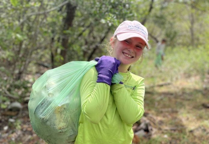 Marine-Debris-Derby-1 a woman carrying a bag of garbage in the woods