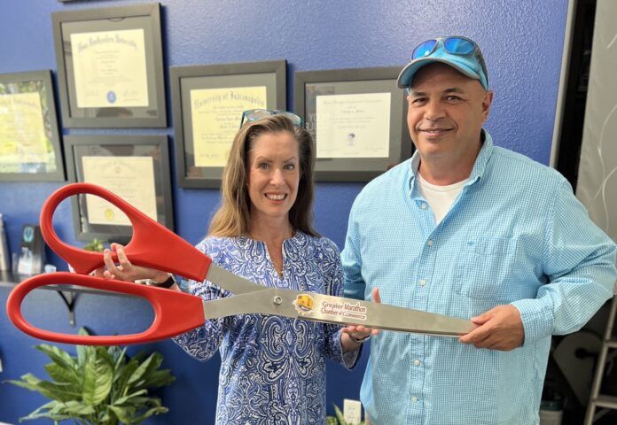 a man and woman holding a giant pair of scissors