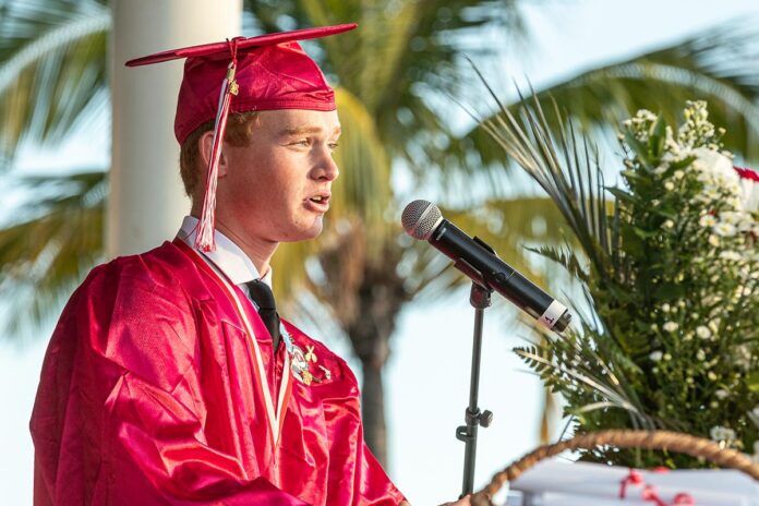 John Searcy valedictorian a man in a graduation gown speaking into a microphone