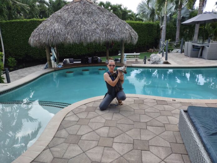 Nicole with Ridley a man sitting next to a swimming pool