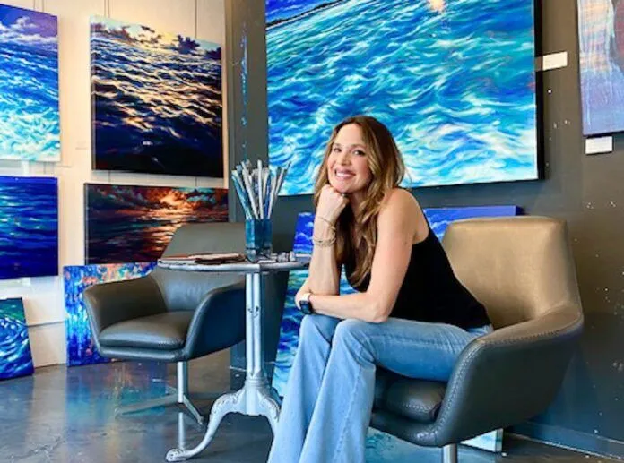 Elena Madden Large a woman sitting on a chair in front of paintings