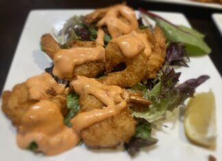 a white plate topped with a salad covered in sauce