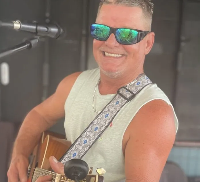 a man with sunglasses on playing a guitar