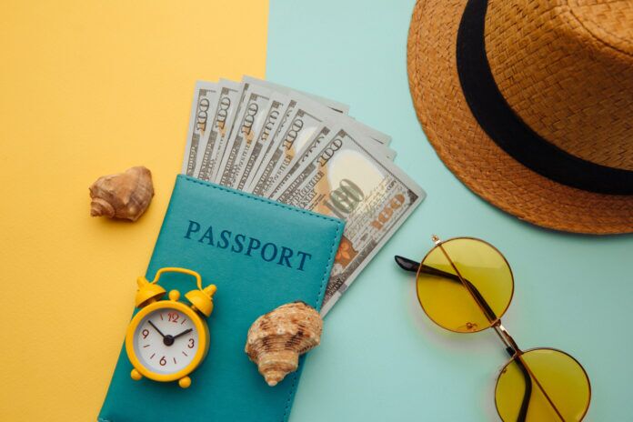 Vacation travel adventure trip concept. Minimal simple flat lay a passport, sunglasses, money, and a hat on a blue and yellow background