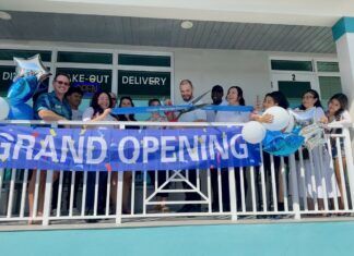 a group of people holding a grand opening banner