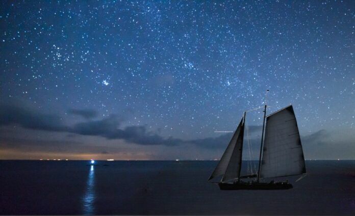 stargazing photo 2 - 1 a sailboat floating in the ocean under a night sky filled with stars