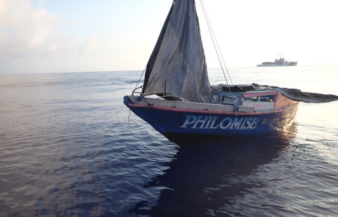 Haitian boat 2024 2 a sailboat in the ocean with a ship in the background