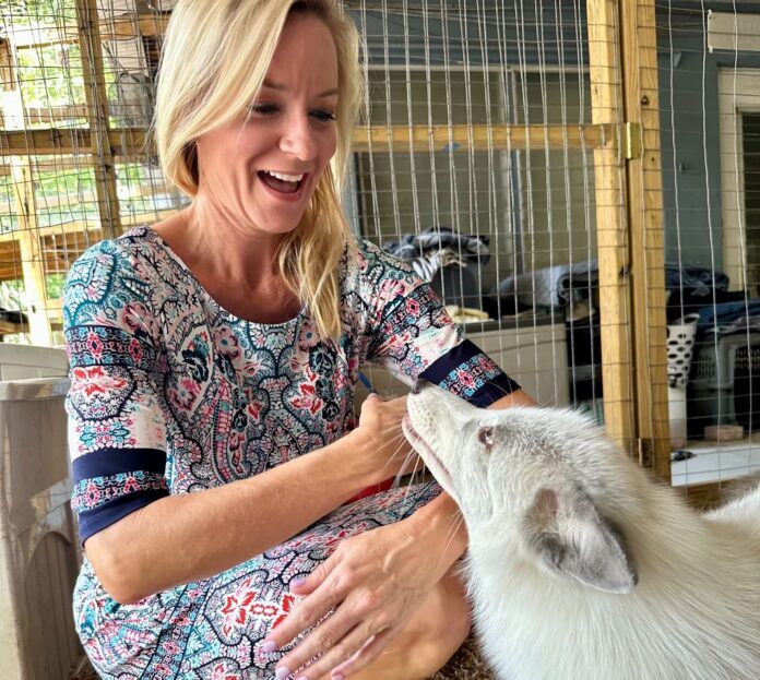 Holly and Reef a woman petting a goat in a cage