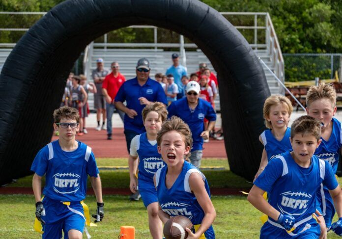UK Flag Football 2 Large a group of young children running across a field