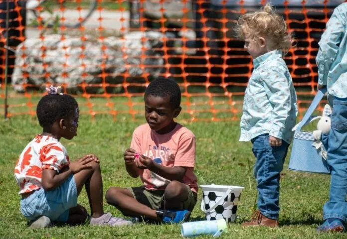 a group of young children sitting on the grass