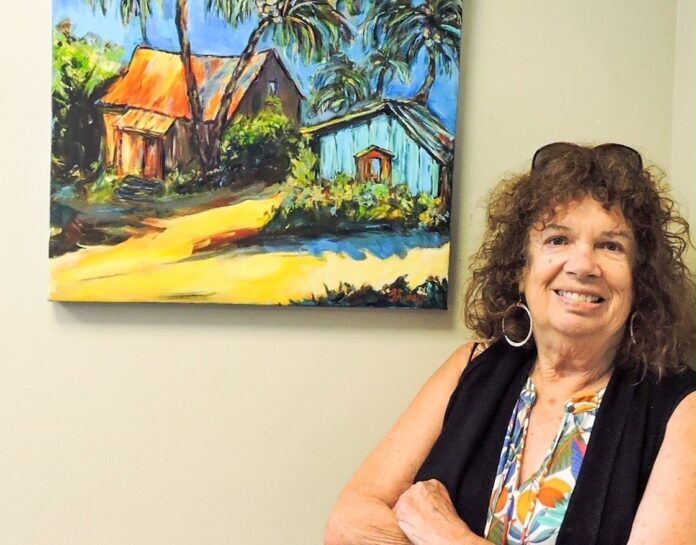 Gloria Avner Large a woman standing in front of a painting