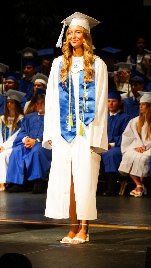 a woman in a graduation gown standing on a stage