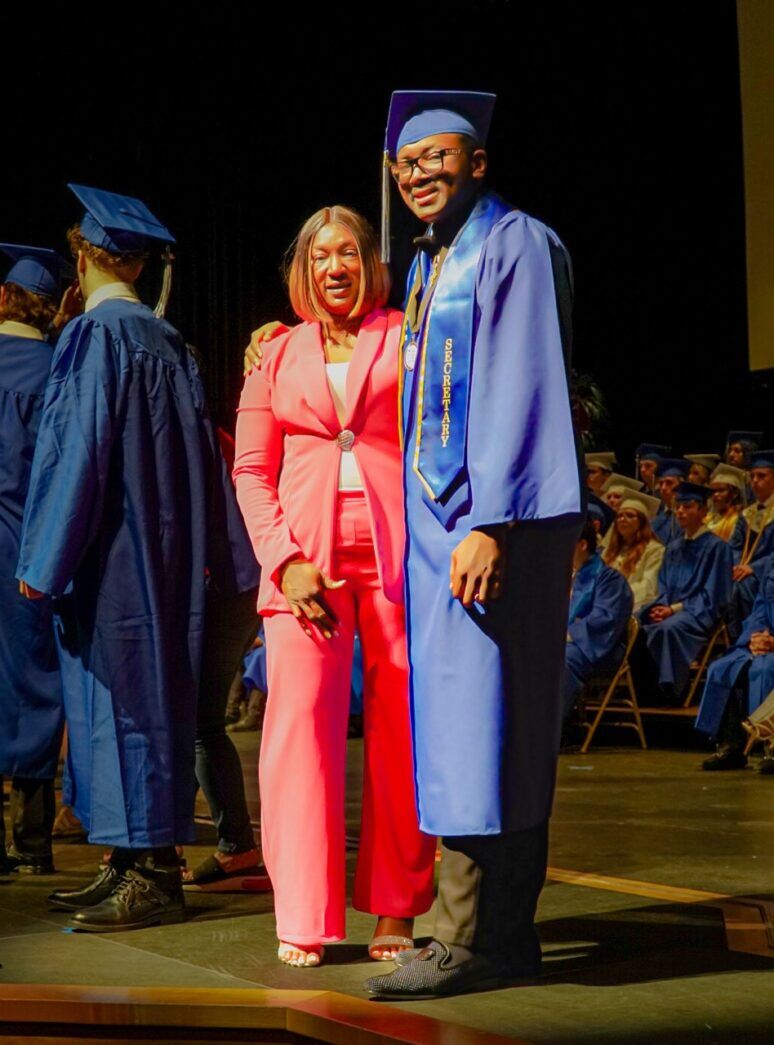 a man and woman in graduation gowns standing on a stage