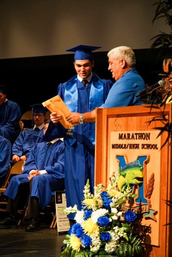 a group of people in graduation gowns standing at a podium