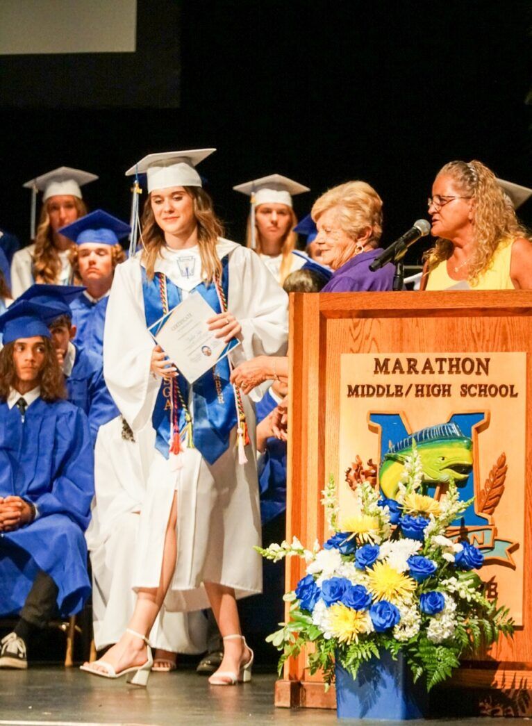 a woman standing at a podium in front of a group of graduates