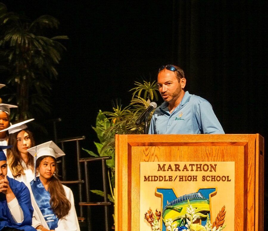 a man standing at a podium in front of graduates