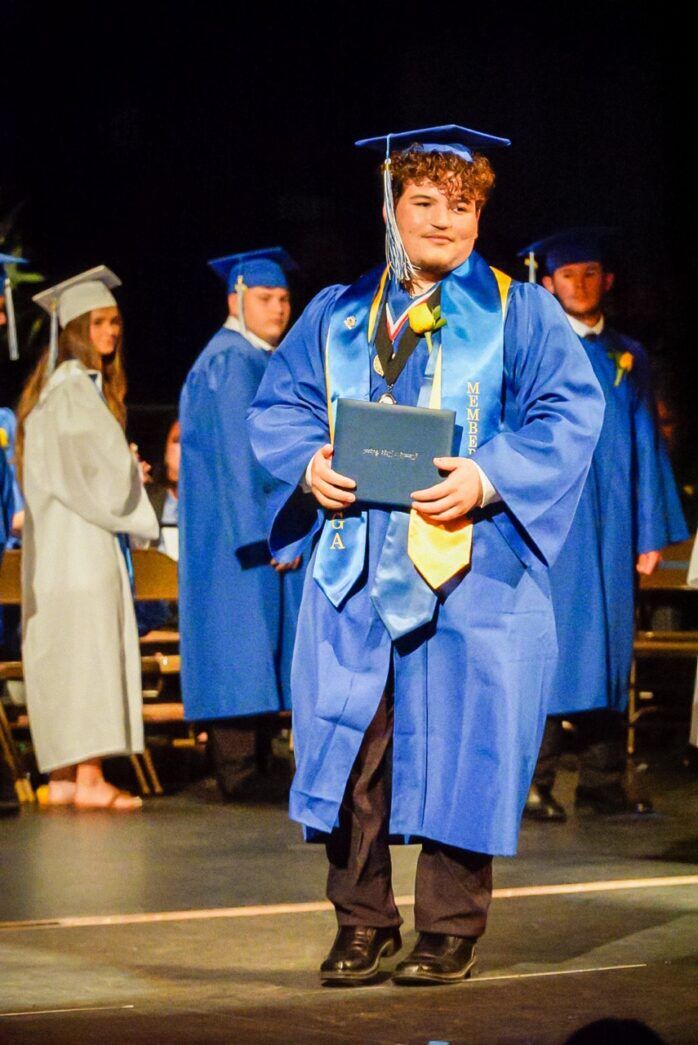 a man in a graduation gown holding a plaque