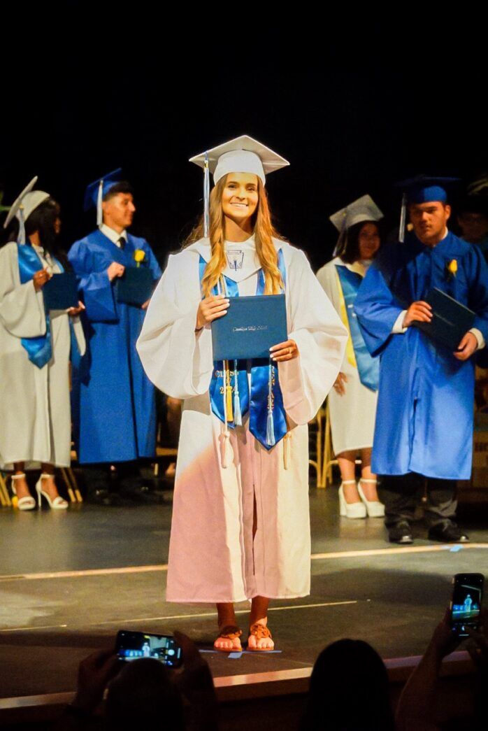 a woman standing on a stage holding a diploma