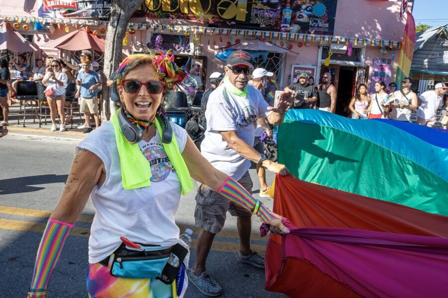 a woman holding a rainbow colored umbrella in the street