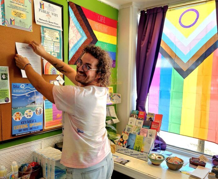 Chris at Queer Keys center Large a man standing in front of a bulletin board
