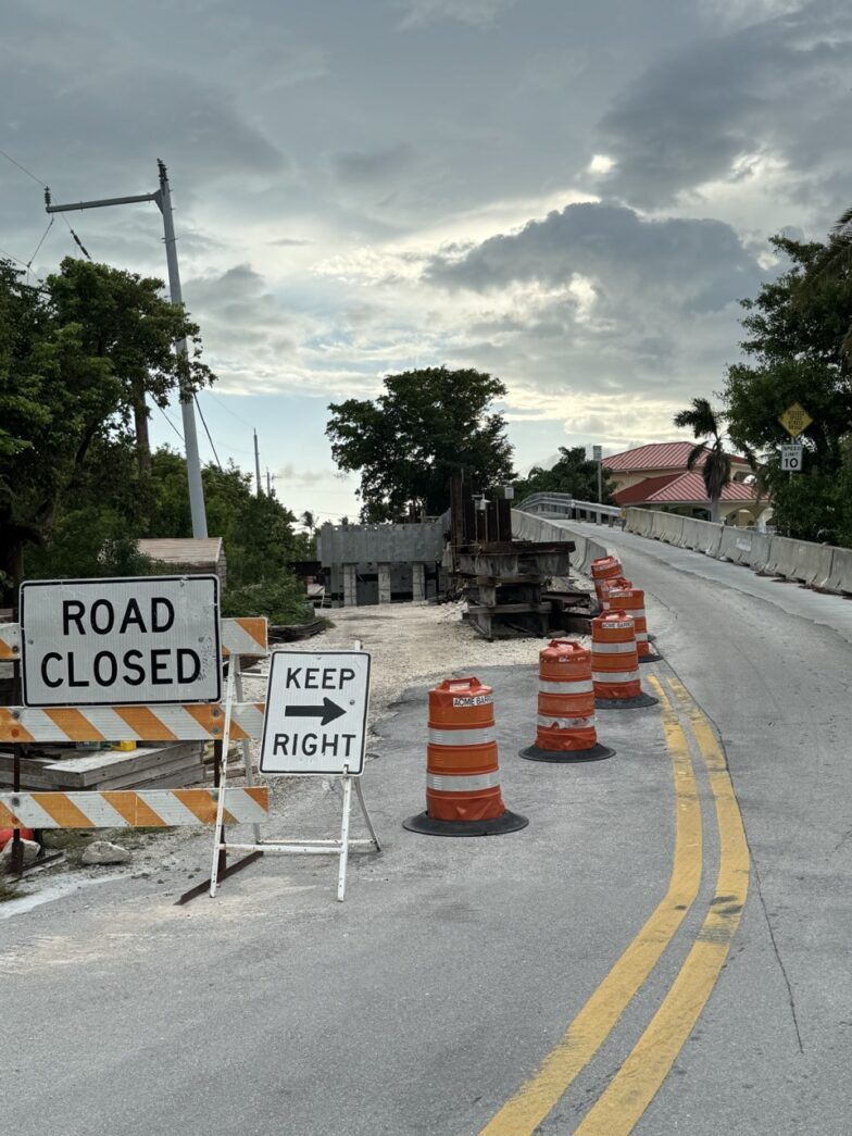 a road closed sign next to construction cones