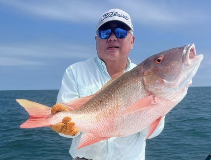 Screenshot a man on a boat holding a large fish